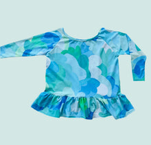 Blue and green patterned long-sleeve top on a light gray background