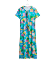 A short-sleeve shift dress with a colorful geometric block pattern in shades of blue, green, pink, yellow, and orange, laid flat on a white sheet of paper with a tie belt at the neckline.