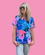 Person wearing a colorful floral-patterned shirt against a plain background