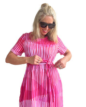 Woman wearing a pink and white striped dress against a plain background